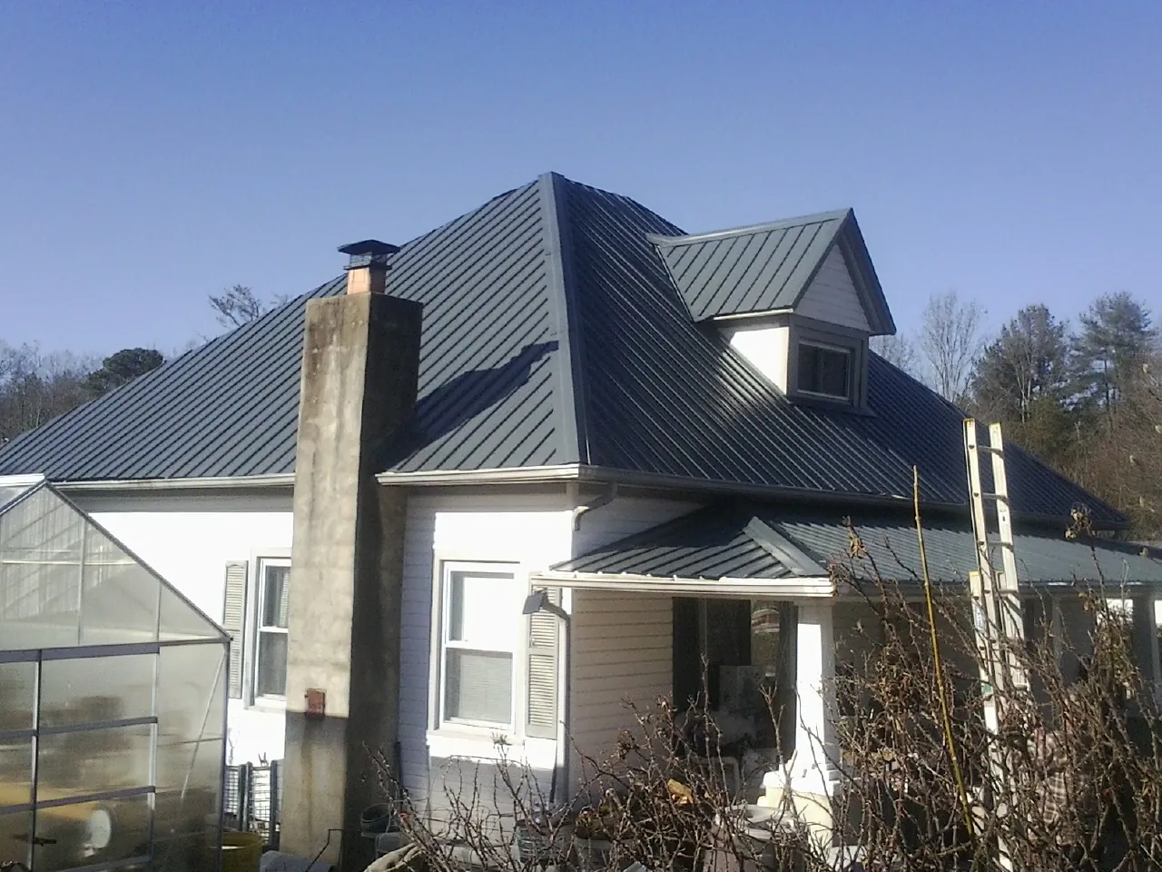 Dark blue standing seam metal roof on a white farmhouse with dormer — Slate & Tile Roof Repair by Roofing Brothers in Piscataway