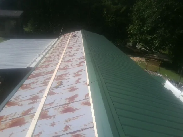 Old rusted panels beside newly installed green metal roofing — Wind Damage Roof Repair by Roofing Brothers in Piscataway