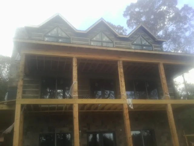 Dormers and porch framing on a large log home under construction — Roof Coating work by our crew in Piscataway