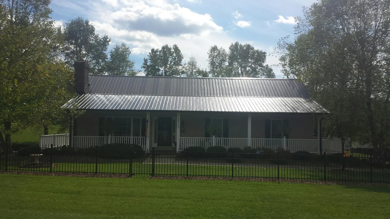 Gray metal roof on a brick ranch with a full width front porch — Gutter Guard Installation work by our crew in Piscataway