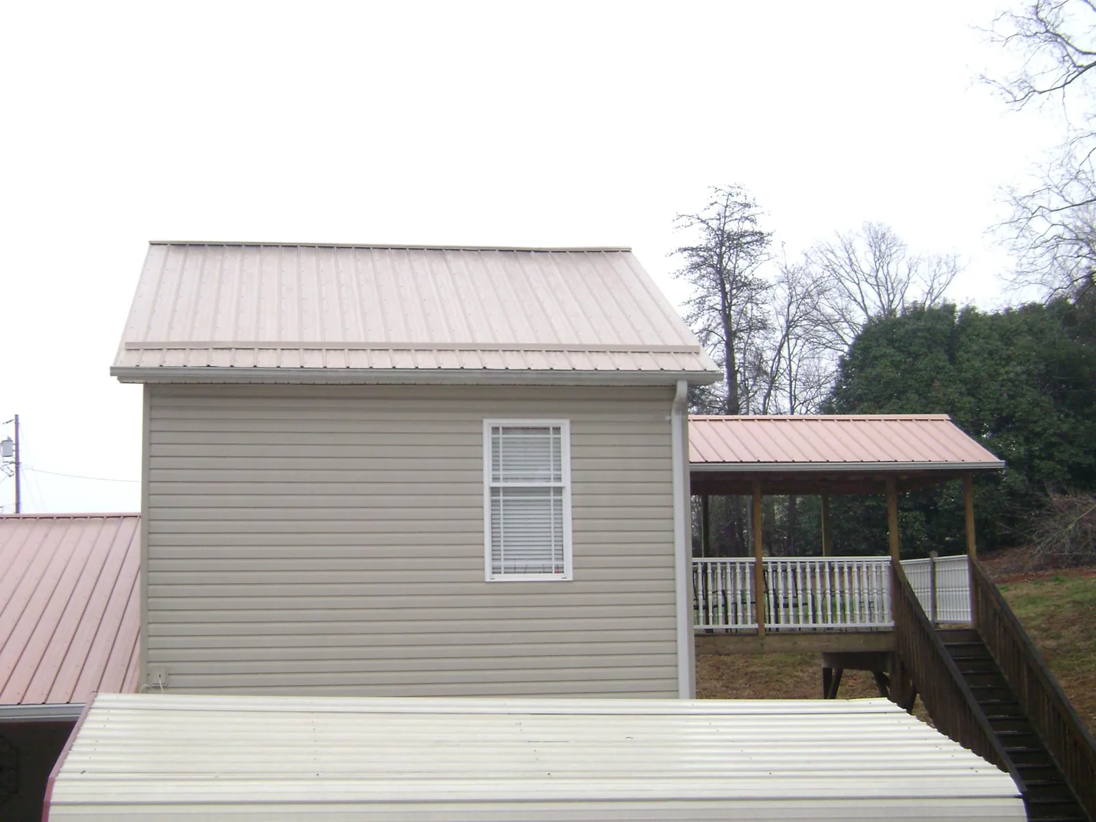 Tan metal roofs on a two story addition and attached porch, from a Roof Replacement job in Piscataway
