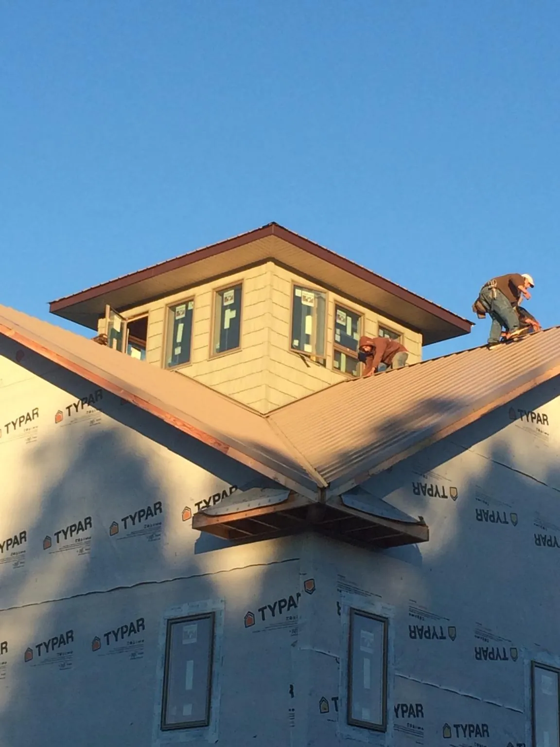 Roofers working around a rooftop cupola on a new metal roof at sunset — Roof Waterproofing in Piscataway by Roofing Brothers